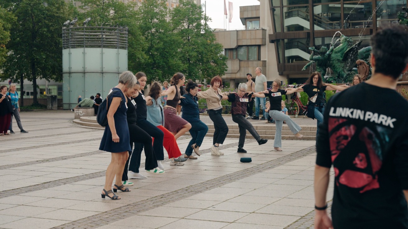 Tänzerinnen und Passantinnen tanzen gemeinsam beim Follow the Beat Flashmob auf dem Augustusplatz